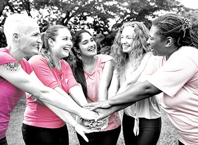 Women supporting one another at a breast cancer awareness event